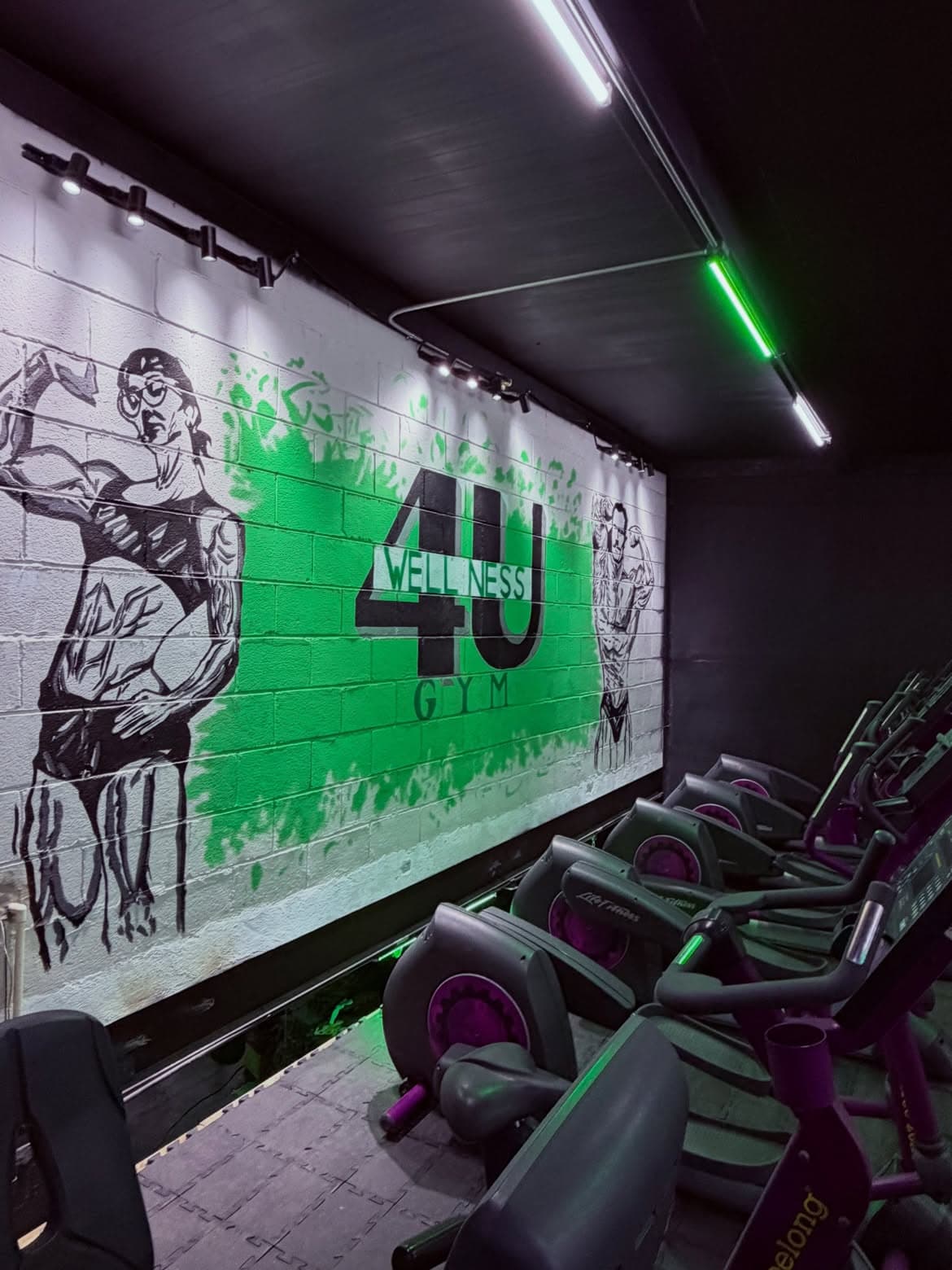 Máquinas de cardio frente al mural de 4U Wellness Gym